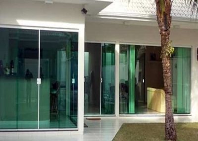 janela de vidro verde temperado com perfil de acabamento em alumínio branco.